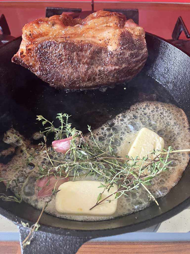 steak with butter, thyme, and garlic in skillet