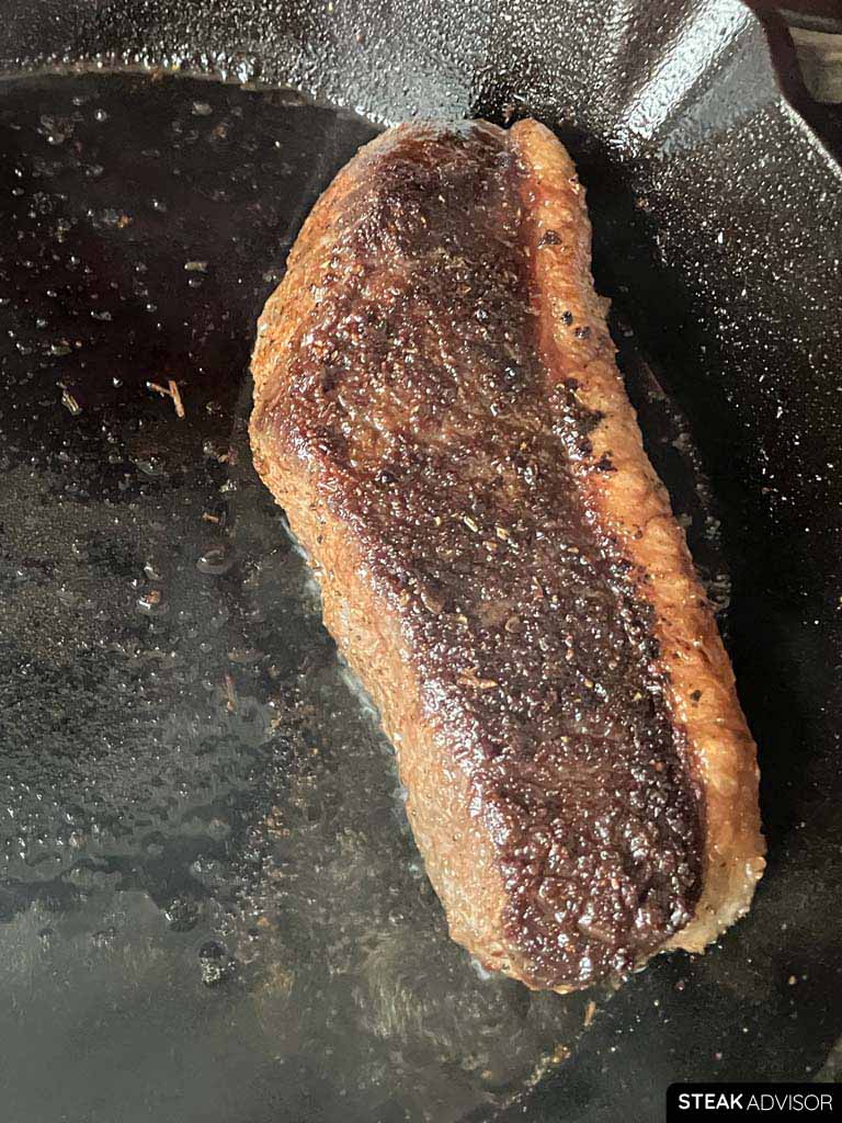 blackened steak seared in a pan vertical view